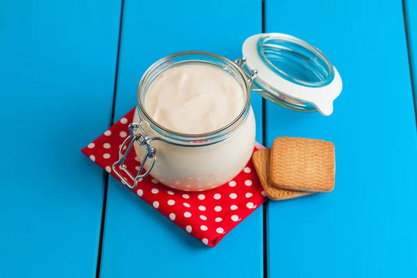 Mavi ahşap bir masa üzerinde ev yapımı yoğurt.