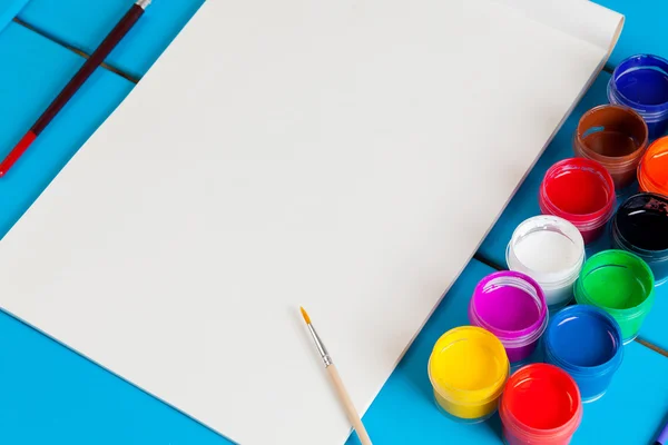 Albüm sayfaları ve boya, fırça bir mavi ahşap arka plan üzerinde.