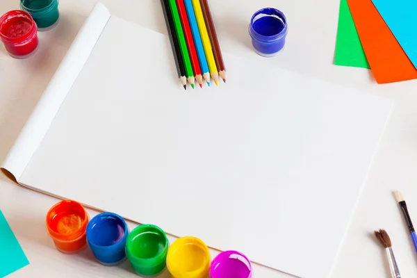 Beyaz ahşap backgro üzerinde albüm sayfaları ve boya, kalem, fırça