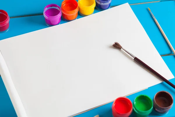 Albüm sayfaları ve boya, fırça bir mavi ahşap arka plan üzerinde.