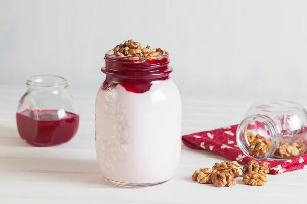 Iogurte caseiro com geléia e nozes em um jarro em uma madeira branca — Fotografia de Stock