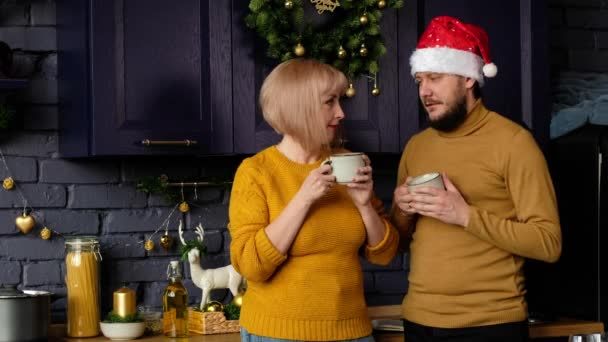 Happy man and a woman drink tea and kiss in the kitchen, on Christmas and New year eve. — Stock Video