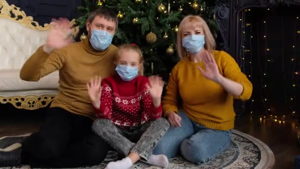 Šťastná rodina slaví Vánoce se svými přáteli pomocí videohovoru. Rodiče a děti v lékařských maskách zdraví své příbuzné na Nový rok on-line. — Stock video