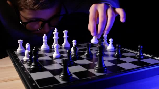 Enfant jouant aux échecs à table. Petit garçon avec des lunettes développant une stratégie d'échecs, jouer au jeu de plateau avec un ami. — Video