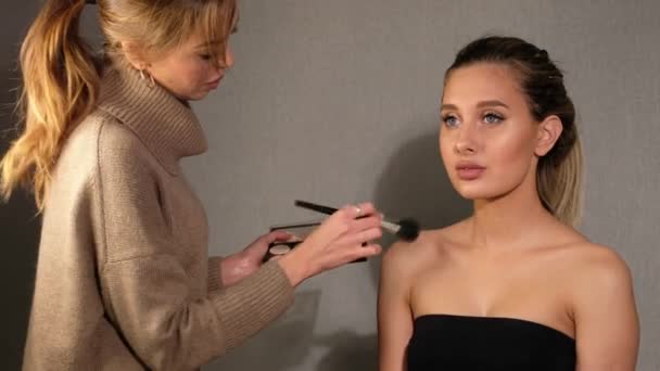 Processen att göra makeup. Make-up artist arbetar med borste på modell kvinna ansikte. — Stockvideo