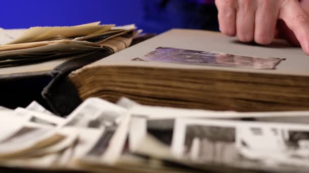 Starsza kobieta przegląda rodzinny album ze starymi zdjęciami przy stole w domu. — Wideo stockowe