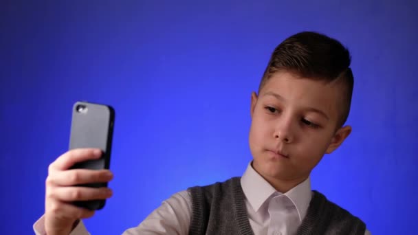 Красивый школьник делает селфи на телефоне. Современный ребенок фотографируется на смартфоне. — стоковое видео