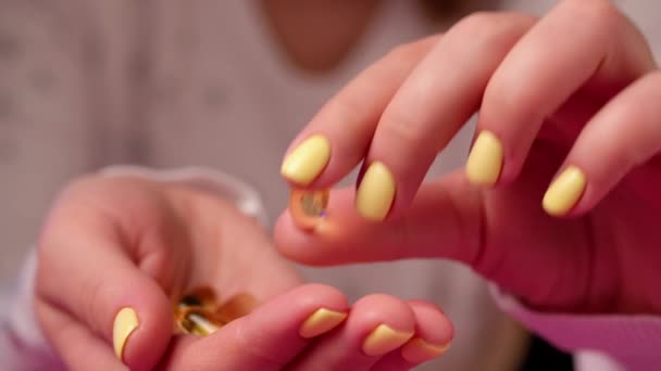 A mulher tem cápsulas de óleo de peixe nas mãos. Comprimidos ómega 3 amarelos. — Vídeo de Stock