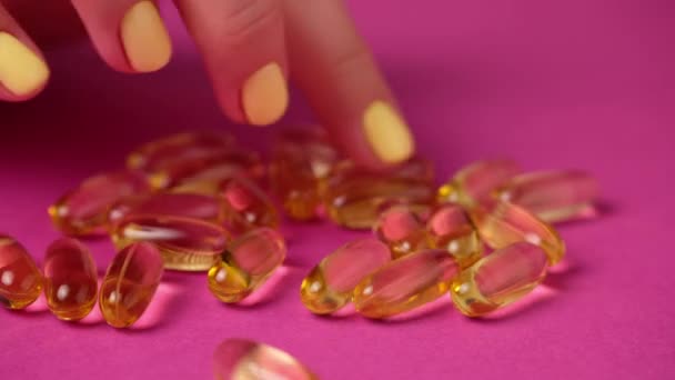 Mulher toca cápsulas com os dedos. Comprimidos ómega 3 amarelos. — Vídeo de Stock