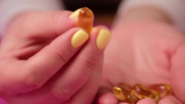 A nő halolaj kapszulát tart a kezében. Sárga omega 3 tabletta. — Stock videók