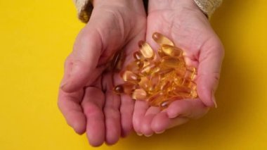 Yaşlı kadın balık yağı kapsüllerini elinde tutuyor. Omega 3 ve yaşlılık.