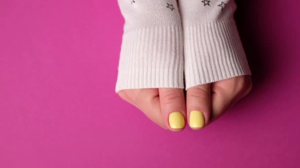 Kobieta w swetrze pokazuje manicure na fioletowym tle. dziewczyna wykonane żel paznokcie polski. — Wideo stockowe