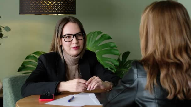 Die schöne Geschäftsfrau mit Brille und Sakko spricht mit der Frau am Tisch. Psychologe spricht mit Patient. — Stockvideo