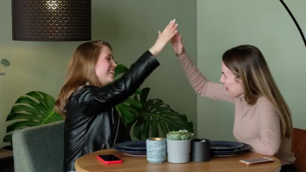 Jeunes femmes modernes haut cinq et câlin dans le café. Les amis sont heureux avec le succès. — Video