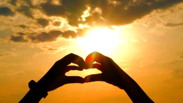 Mâinile femeii formează o formă de inimă cu siluetă de apus de soare . — Videoclip de stoc