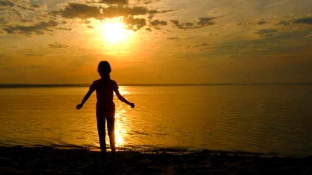 Silueta de niña niño feliz saltando en la arena de la playa al atardecer. — Vídeos de Stock