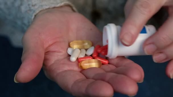 Old woman takes pills. Elderly pensioner holds pill in her hand and drinks them. — Stock Video