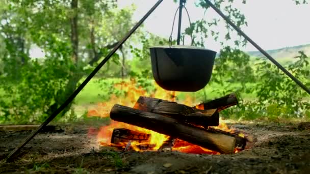 Turistler kamp alanındaki kamp ateşinde yürüyüş kampında öğle yemeği hazırlıyorlar. Bowling şenlik ateşinde. — Stok video