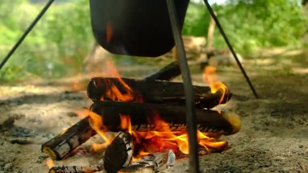 La gente prepara el almuerzo en la olla de senderismo en la fogata en el campamento. Bowler en hoguera. — Vídeo de stock