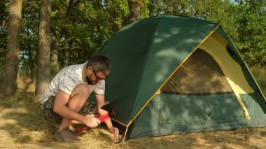 Sakallı adam turist kampında çadır kuruyor. Baltalı dişi çekiç mandalı..