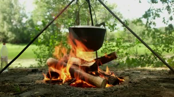 Turister förbereder lunch i vandringskruka på lägereld på campingen. Bowlare på brasan. — Stockvideo