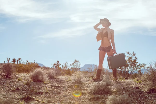 woman traveler walking with suitcase in desert