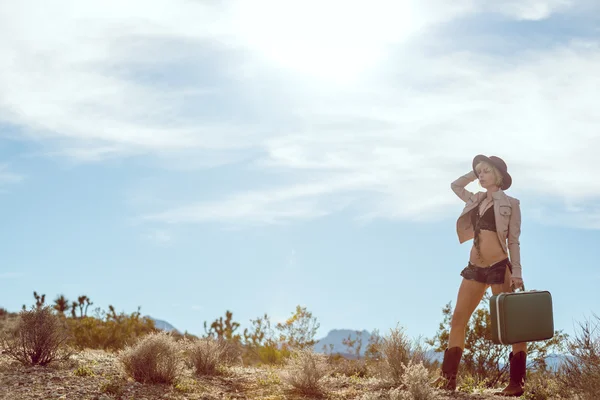 Viajero mujer caminando con maleta en el desierto — Foto de Stock