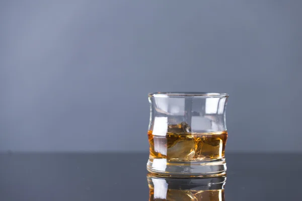 Whisky op de rotsen op de glazen tafel — Stockfoto