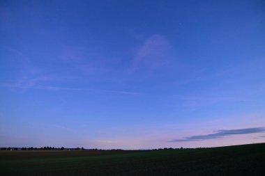 Night sky with stars and clouds over a peaceful field, beautiful nature composition and atmospheric landscape.