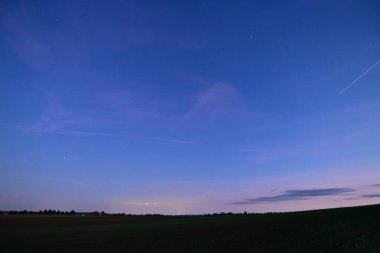 Night sky with stars and clouds over a peaceful field, beautiful nature composition and atmospheric landscape.