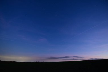 Night sky with stars and clouds over a peaceful field, beautiful nature composition and atmospheric landscape.