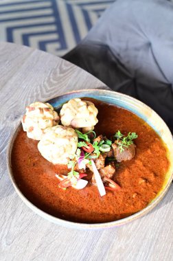 Geleneksel Çek tas kebabı ve ekmek hamuru bir restoranda ahşap bir masada servis ediliyor. Soğanlı ve kırmızı biber soslu zengin sığır güveci, taze otlarla süslenmiş klasik bir Çek konfor yemeği ve özgün ulusal yemek..