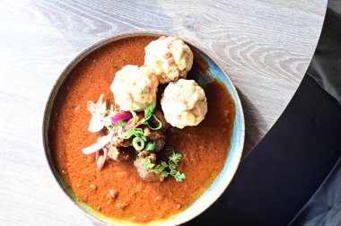 Geleneksel Çek tas kebabı ve ekmek hamuru bir restoranda ahşap bir masada servis ediliyor. Soğanlı ve kırmızı biber soslu zengin sığır güveci, taze otlarla süslenmiş klasik bir Çek konfor yemeği ve özgün ulusal yemek..