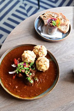 Geleneksel Çek geyik kebabı, kırsal bir ahşap masada bir restoranda servis edilir. Yemek güzel bir şekilde ekmekli börek, karamelli soğan ve dekorasyon için kırmızı biber ile sunuluyor.