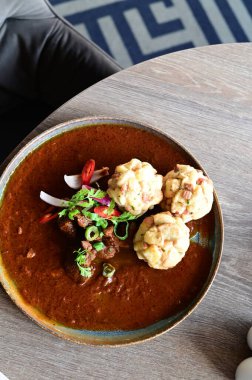Geleneksel Çek geyik kebabı, kırsal bir ahşap masada bir restoranda servis edilir. Yemek güzel bir şekilde ekmekli börek, karamelli soğan ve dekorasyon için kırmızı biber ile sunuluyor.