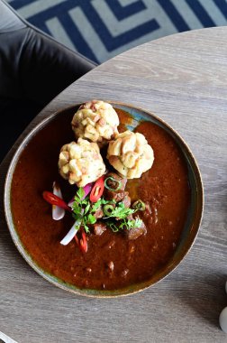 Geleneksel Çek geyik kebabı, kırsal bir ahşap masada bir restoranda servis edilir. Yemek güzel bir şekilde ekmekli börek, karamelli soğan ve dekorasyon için kırmızı biber ile sunuluyor.