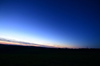 Büyük Ayı takımyıldızı, kuyruklu yıldız Lemmon ve yıldız bağlantı uydularıyla dolu renkli bir ufukta gün batımı..
