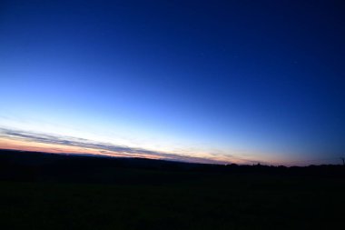 Büyük Ayı takımyıldızı, kuyruklu yıldız Lemmon ve yıldız bağlantı uydularıyla dolu renkli bir ufukta gün batımı..