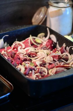 Kızartma için soğanlı çiğ yaban domuzu eti, geleneksel Çek yemeklerinin arka planını gösteriyor. Kırsal bir mutfak sahnesi, oyun etinin otantik hazırlığını ve klasik Çek vypeki yapma sürecini yakalıyor..