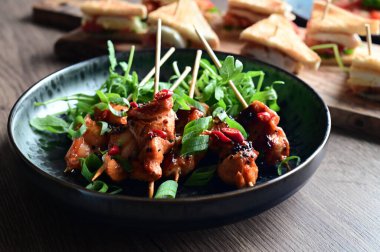 Izgara tavuk kanadı, sebzeli ve soslu, koyu arkaplanda.