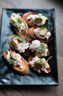 Kremalı ve somonlu bruschetta. Tahta tabakta.