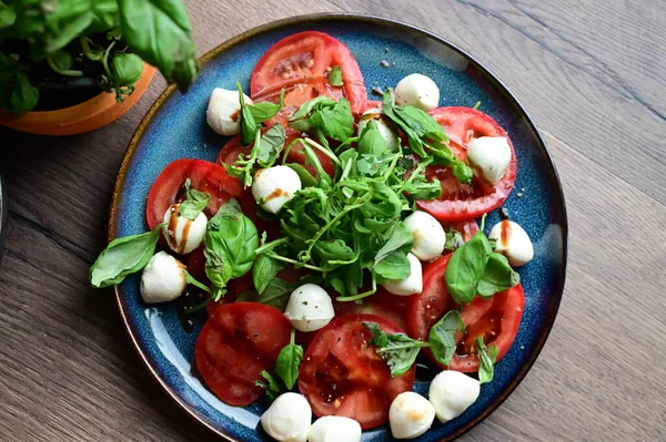 Bebek mozarella, olgun domatesler ve bitkilerle taze Caprese salatasının en iyi görüntüsü. Renkli ve canlı sunum, geleneksel İtalyan mutfağının içeriğinin tazeliğini ve basitliğini vurguluyor..