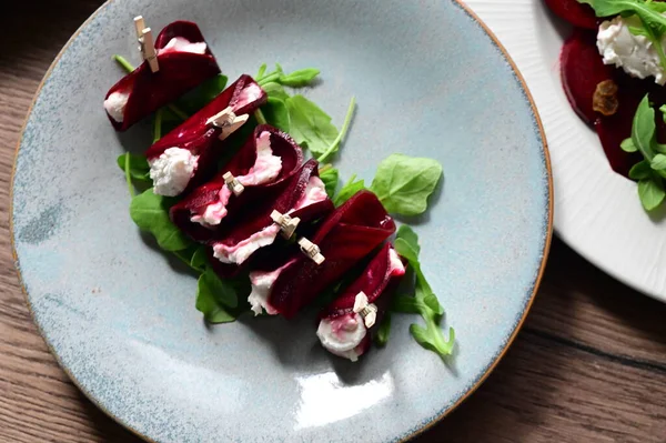 Beyaz tabakta roka ve peynir pancar salatası.