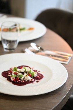 Kızarmış kırmızı pancar, taze otlar, keçi peyniri ve fıstık içeren vejetaryen yemeği.,