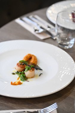 Deniz tarağı (St. Jacques), taze otlar ve ahşap bir masa üzerindeki bir restoranda zarif bir şekilde kaplanmış balkabağı içeren renkli aperatifler. Gurme, güzel yemekler ve aşçılık projeleri için mükemmel..