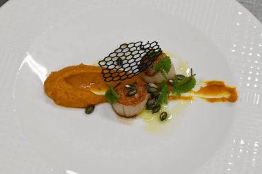 Kabak püresi, gurme aperatifi, bir restoranda beyaz tabakta servis edilen deniz tarakları, yakın çekim yemek fotoğrafçılığı, zarif bir yemek sunumu.,