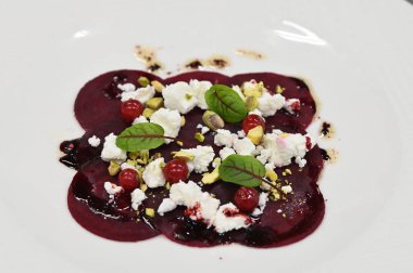 Pancar carpaccio beyaz bir tabakta servis edilir, bir restoranda modern vejetaryen yemeğine yakın çekim, zarif bir yemek sunumu, sağlıklı gurme mutfağı,