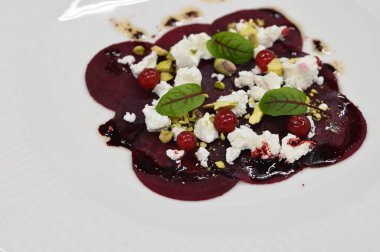 Pancar carpaccio beyaz bir tabakta servis edilir, bir restoranda modern vejetaryen yemeğine yakın çekim, zarif bir yemek sunumu, sağlıklı gurme mutfağı,