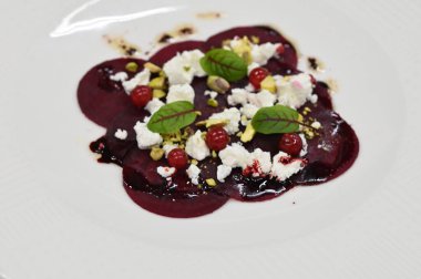 Pancar carpaccio beyaz bir tabakta servis edilir, bir restoranda modern vejetaryen yemeğine yakın çekim, zarif bir yemek sunumu, sağlıklı gurme mutfağı,