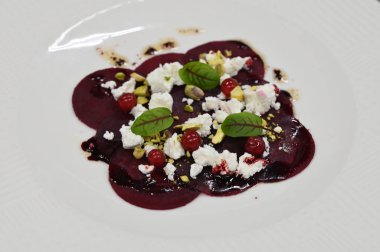 Pancar carpaccio beyaz bir tabakta servis edilir, bir restoranda modern vejetaryen yemeğine yakın çekim, zarif bir yemek sunumu, sağlıklı gurme mutfağı,